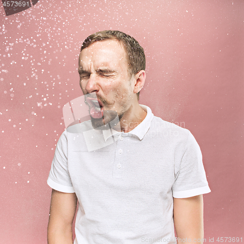 Image of Young handsome man with beard sneezing, studio portrait