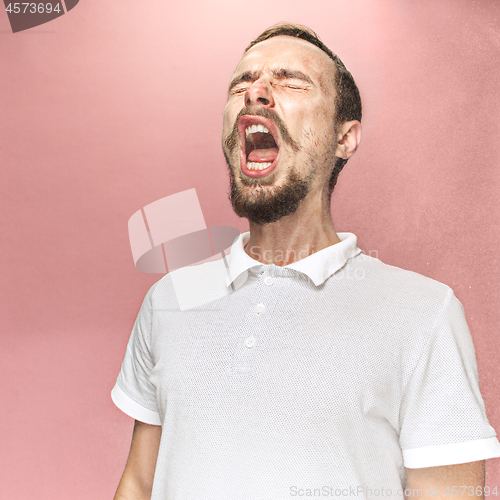 Image of Young handsome man with beard sneezing, studio portrait