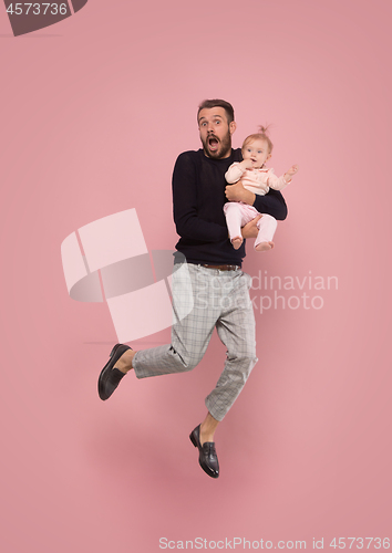 Image of The studio shot of little girl sitting on his father. isolated on pink