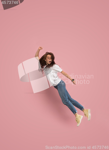 Image of Freedom in moving. Pretty young woman jumping against pink background