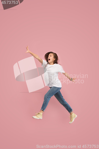 Image of Freedom in moving. Pretty young woman jumping against pink background