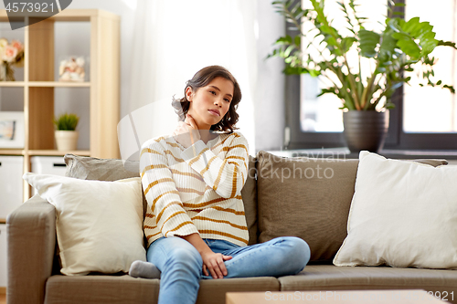 Image of unhappy woman suffering from neck pain at home