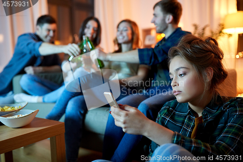 Image of sad young woman with smartphone at home party