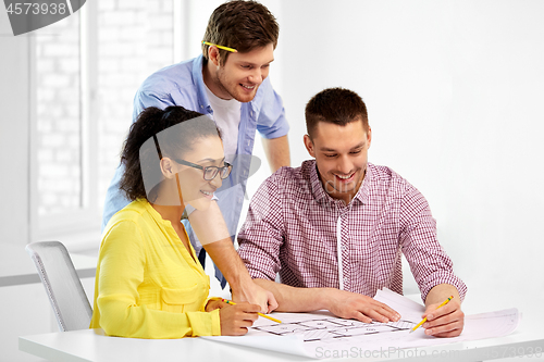 Image of creative team with blueprint working at office