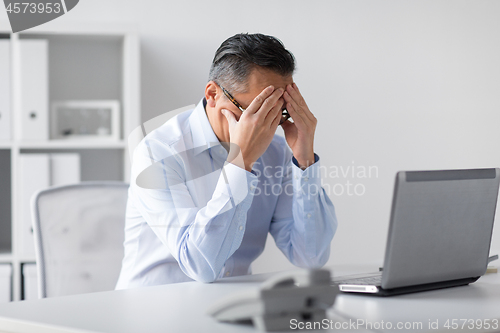 Image of stressed businessman with laptop working at office