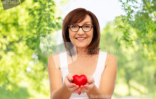 Image of portrait of smiling senior woman holding red heart