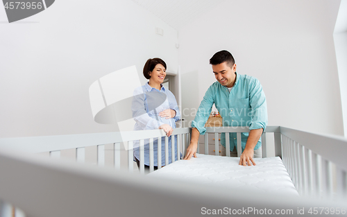 Image of family couple arranging baby bed with mattress