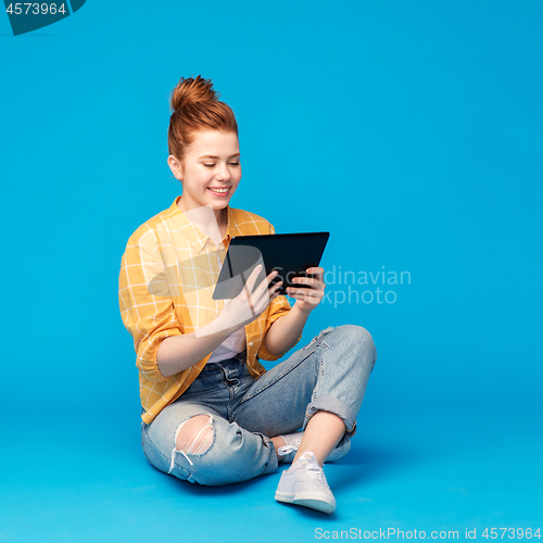 Image of red haired teenage girl using tablet computer