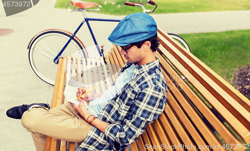 Image of man with notebook or diary writing on city street