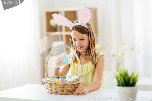 Image of happy girl with colored easter eggs at home