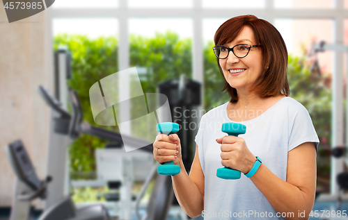 Image of happy old woman with dumbbells exercising in gym