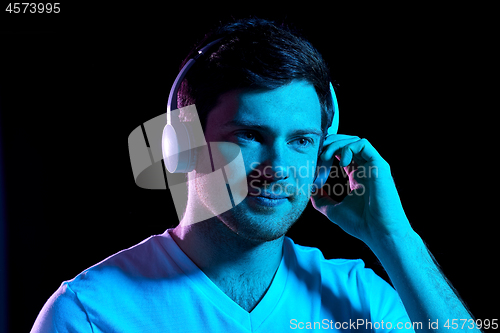 Image of man in headphones over neon lights of night club