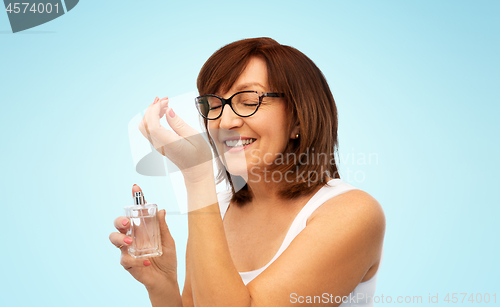 Image of senior woman smelling perfume from her wrist