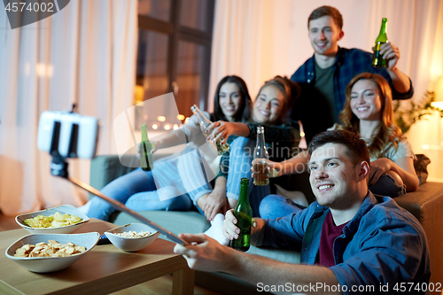 Image of friends taking picture by selfie stick at home