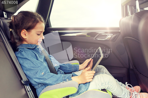 Image of happy little girl with tablet pc driving in car