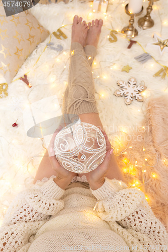 Image of Female holds a glittering bauble among Chrismas decorations