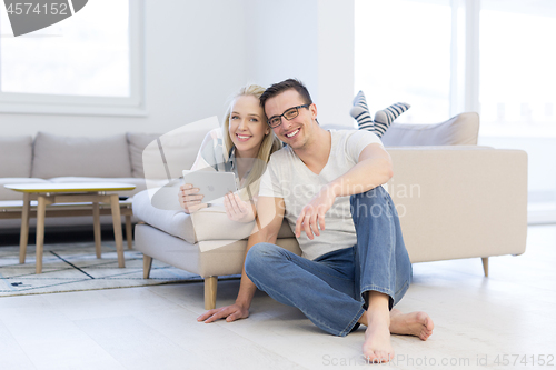 Image of couple relaxing at  home with tablet computers