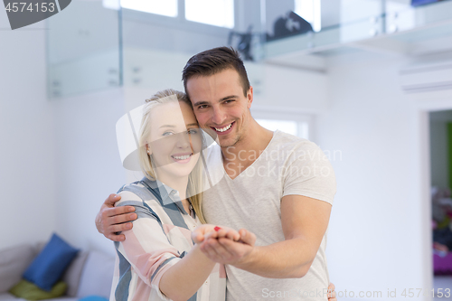 Image of couple showing small red house in hands