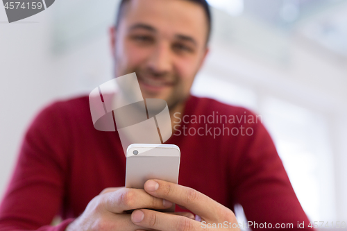 Image of young man using a mobile phone  at home