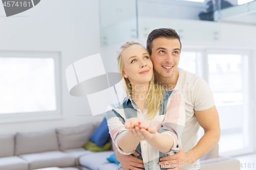 Image of couple showing small red house in hands