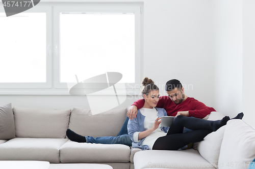 Image of couple relaxing at  home with tablet computers