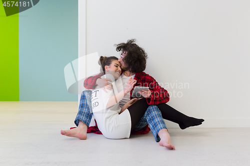 Image of Young Couple using digital tablet on the floor