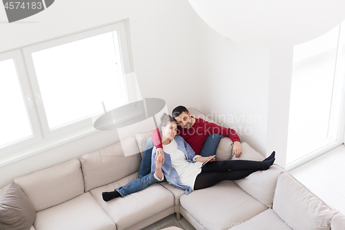 Image of couple relaxing at  home with tablet computers