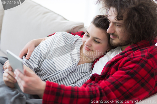 Image of couple relaxing at  home with tablet computers