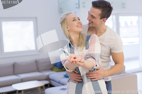 Image of couple showing small red house in hands