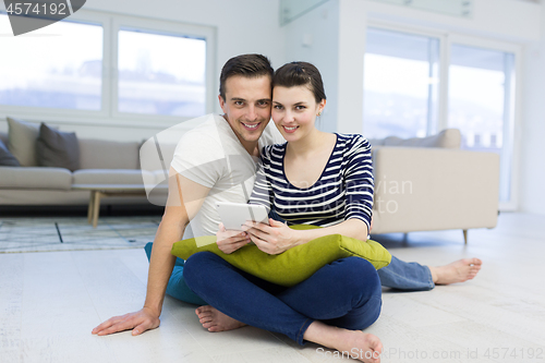 Image of Young Couple using digital tablet on the floor