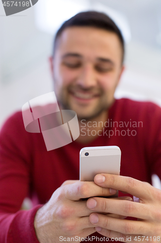 Image of young man using a mobile phone  at home