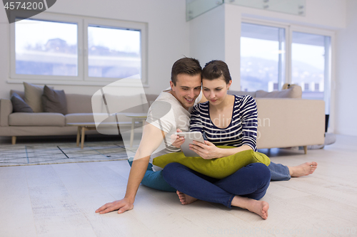 Image of Young Couple using digital tablet on the floor