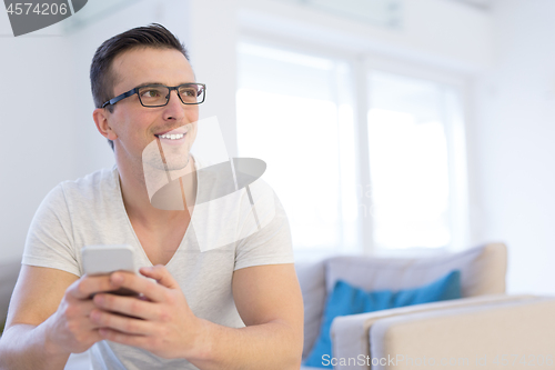 Image of young man using a mobile phone  at home