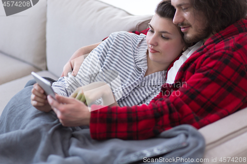 Image of couple relaxing at  home with tablet computers