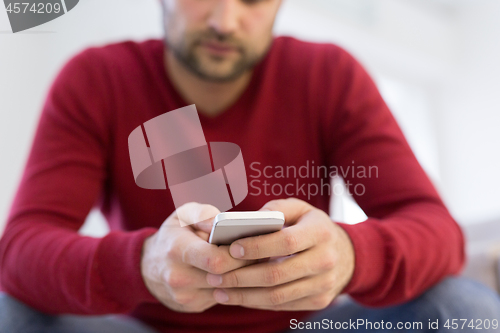 Image of young man using a mobile phone  at home