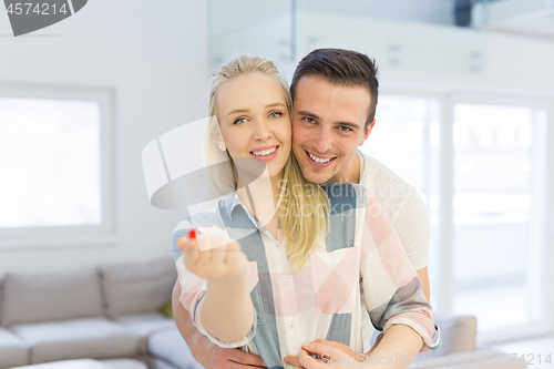 Image of couple showing small red house in hands