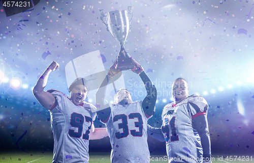 Image of american football team with trophy celebrating victory in the cu