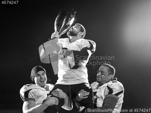 Image of american football team with trophy celebrating victory