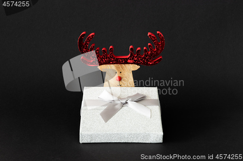 Image of Christmas decoration reindeer with silver gift box on a black ba