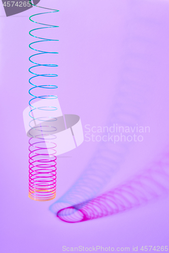 Image of Rainbow plastic spring toy with two duotone shadows.