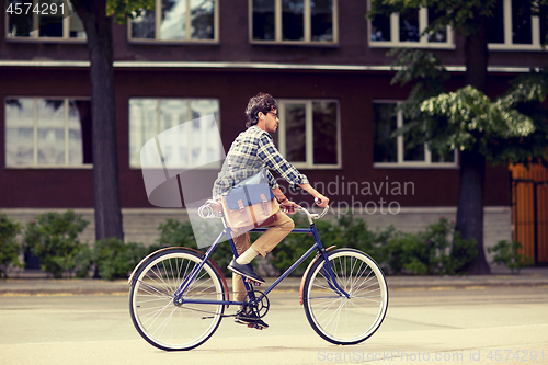 Image of young hipster man with bag riding fixed gear bike