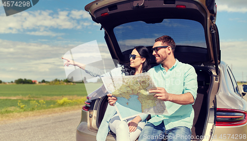 Image of happy man and woman with road map at hatchback car