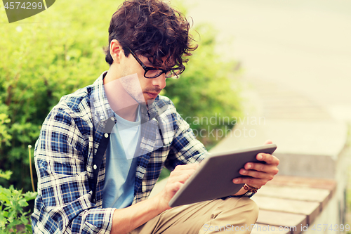 Image of man with tablet pc sitting on city street bench