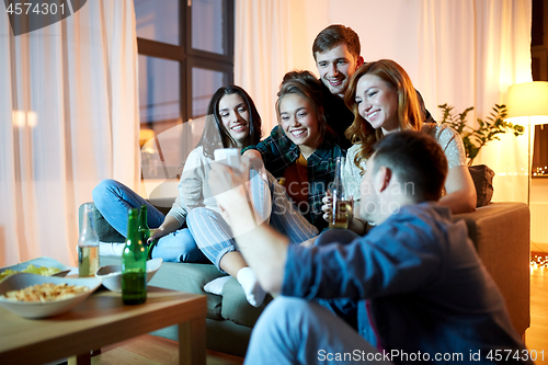 Image of happy friends with smartphone at home party