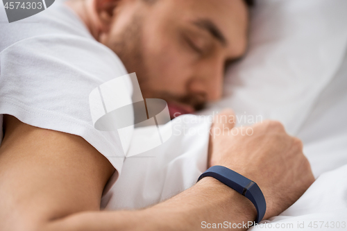 Image of close up of man sleeping with activity tracker