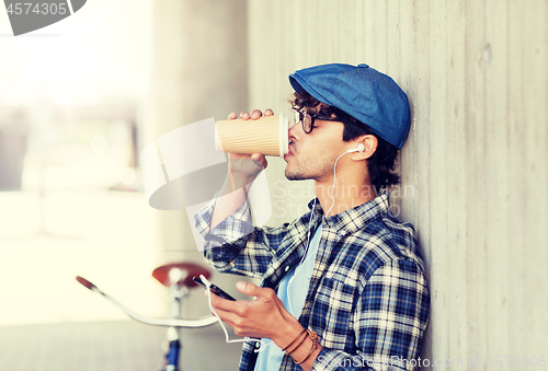 Image of man with earphones and smartphone drinking coffee