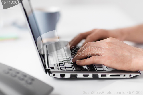 Image of hands typing on laptop computer at office