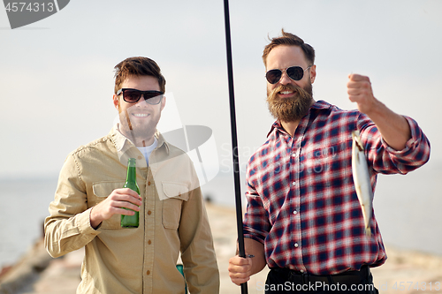 Image of happy friends with fishing rods and beer on pier