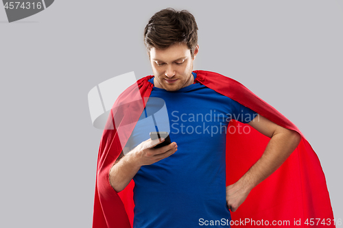 Image of young man in red superhero cape using smartphone