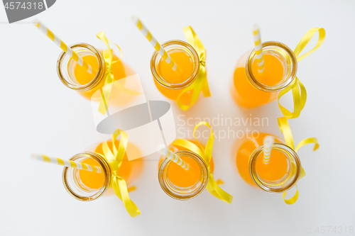 Image of orange juice in glass bottles with paper straws